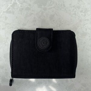 Black Kipling wallet with snap and zipper.